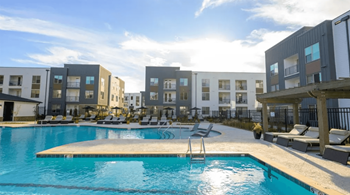A swimming pool in front of a row of apartment buildings.